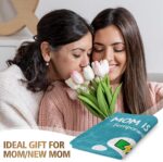 A blue-green Craftique throw blanket with "Mom is Charging" text, folded on a sofa, representing a cozy gift for moms.