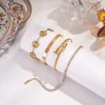 Close-up of four GIVCHO 18K gold plated stainless steel bangle bracelets with clear cubic zirconia stones.