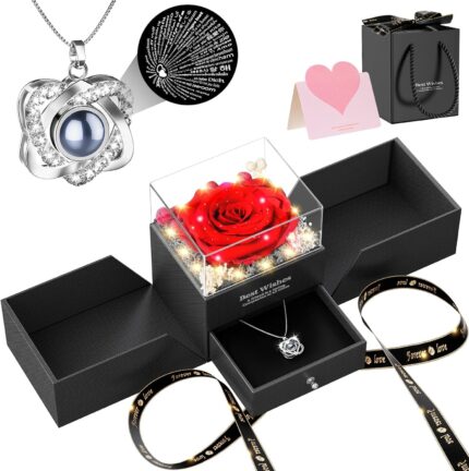A red preserved rose in a gift box with a heart-shaped pendant necklace, illuminated by warm lights.