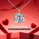 A red preserved rose in a gift box with a heart-shaped pendant necklace, illuminated by warm lights.