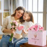 Two large pink floral gift bags with handles, tissue paper, greeting cards, and stickers for Mother's Day gifts.