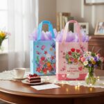 Two SUNCOLOR gift bags, one pink and one blue, with floral and butterfly designs, shown with tissue paper.
