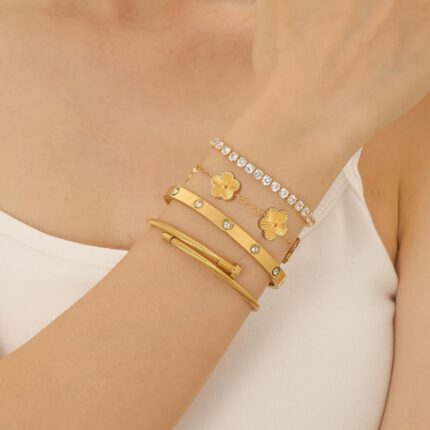 Four Zesnoy 18K gold-plated stackable clover bangle bracelets on a white background, showcasing their shine.
