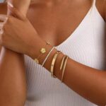 Four Zesnoy 18K gold-plated stackable clover bangle bracelets on a white background, showcasing their shine.